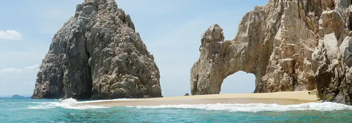 Chiropractic Cabo San Lucas BCS The Beach A view of a beach with giant rock formations sticking out of the water.